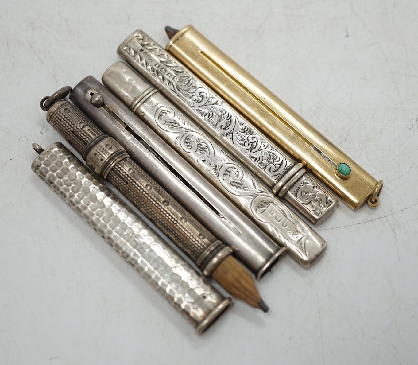 An Edwardian Sampson Mordan & Co 9ct gold and turquoise set cased propelling pencil, closed 74mm, together with five silver cased propelling pencils. Condition - fair